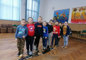 Chłopcy stoją obok swoich butów ustawionych w jednym ciągu.