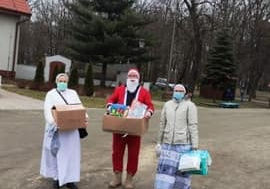 Dwie siostry zakonne i Mikołaj trzymają dary