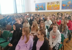 Duża grupa uczniów siedzi w auli
