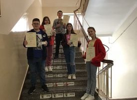 Sześcioro uczniów stoi na schodach z dyplomami