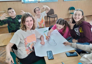 Pięcioro uczniów siedzi przy stole i rysuje