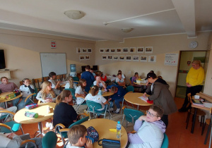 Uczniowie siedzą przy stolikach