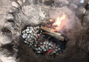 Ziemniaki owinięte folią aluminiową pieką się w ognisku.
