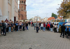 Grupa ludzi stoi przed budynkiem szkoły.