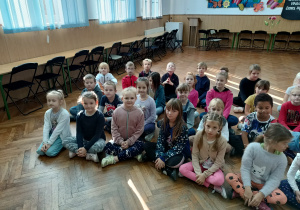 Dzieci z klasy II A siedzą na podłodze na auli.