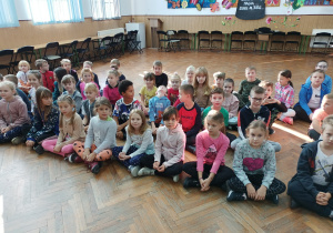 Dzieci z klasy II B siedzą na podłodze na auli.