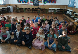 Dzieci z klasy II C siedzą na podłodze na auli.