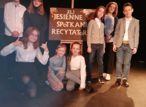 Grupa uczniów stoi przy plakacie "Jesienne Spotkania Recytatorów"