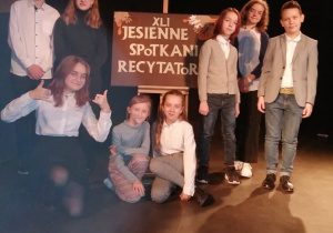 Grupa uczniów stoi przy plakacie "Jesienne Spotkania Recytatorów"