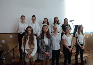 10 dziewczyn stoi i śpiewa kolędy