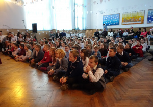 Uczniowie siedzą na podłodze