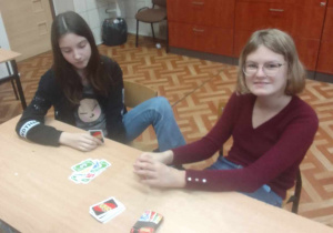 Uczniowie siedzą przy stoliku i grają w gry planszowe