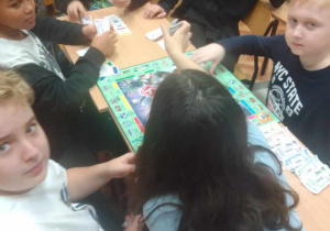 Uczniowie siedzą przy stoliku i grają w gry planszowe