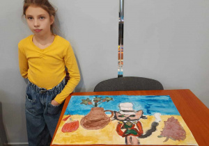 Dziewczynka i jej praca plastyczna z kotem.