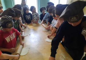 Dzieci stoją przy stole obsypanym mąką