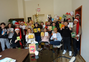 Uczniowie wraz z dyrekcją prezentują przygotowane kartki świąteczne.