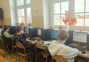 Uczniowie siedzą przy komputerach