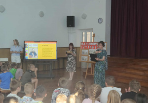 Nauczycielki języka polskiego czytają dzieciom w auli.