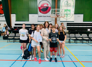 Pani dyrektor stoi z uczniami w strojach sportowych