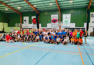 Uczniowie w strojach sportowych stoją na hali