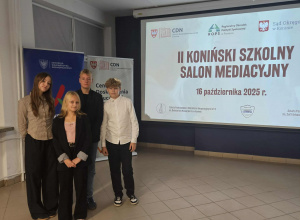Czwóorka uczniów stoi obok slajdu z napisem II Koniński Szkolny Salon Mediacyjny