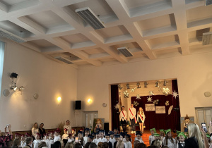 Wszyscy uczniowie w biretach na głowie śpiewają piosenkę.