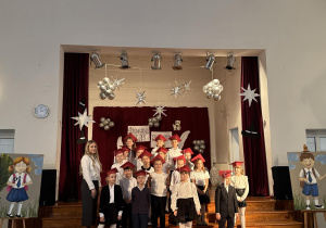 Uczniowie pozują do zdjęcia ze swoją wychowawczynią stojąc na schodach.