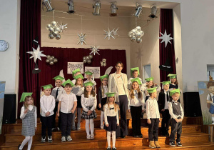 Uczniowie pozują do zdjęcia ze swoją wychowawczynią stojąc na schodach.