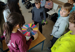 Uczniowie kręcą kołem fortuny, na którym są działania z tabliczki mnożenia.