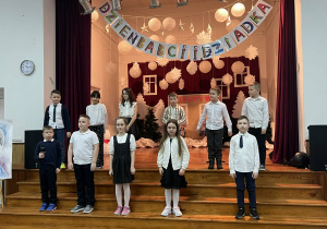 Dzieci recytują wiersze stojąc na schodach.