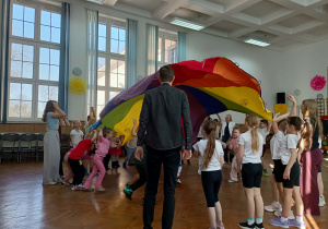 Dzieci bawią się chustą animacyjną, która unosi się w górze.