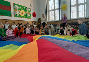 Dzieci siedzą przy chuście animacyjnej.