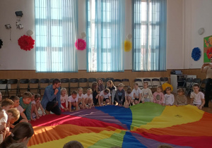 Dzieci siedzą w okręgu wokół chusty.