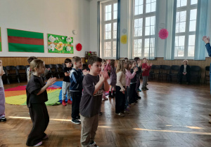 Dzieci tańczą na auli szkolnej.