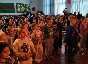 Dzieci tańczą przed sceną na auli.