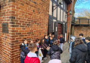 Dzieci próbują się utrzymać przy krzywej wieży w Toruniu.