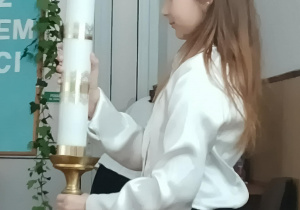 Dziewczynka niesie świecę.