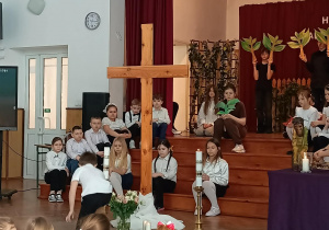 Chłopiec składa świecę pod krzyżem.