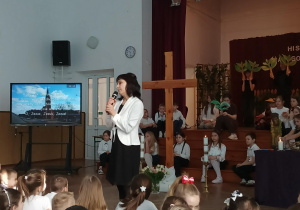 Nauczycielka przemawia do dzieci na auli.