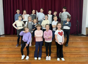 Uczniowie stojąc na schodach pozują do zdjęcia robiąc ciekawe pozy.