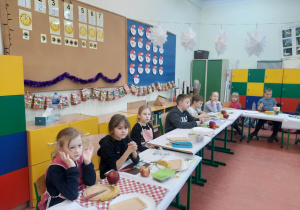 Uczniowie siedzą przy stolikach na warsztatach kulinarnych